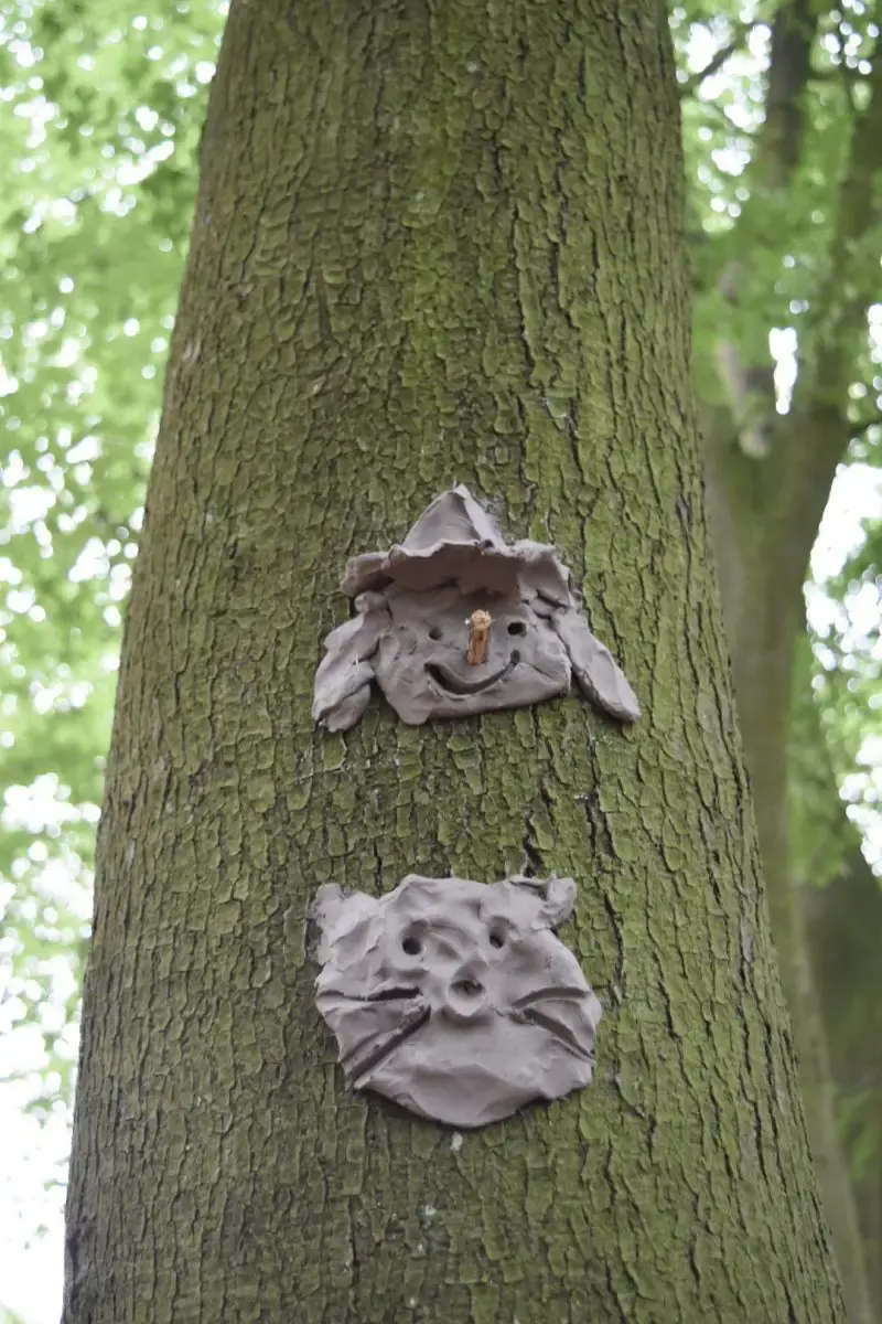 clay face and clay sculptures on a tree trunk for an party with a festival theme idea